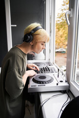 Obraz premium Woman wearing headphones looking at the dj console
