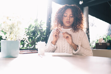 Thoughtful young ethnic female sitting in cafe