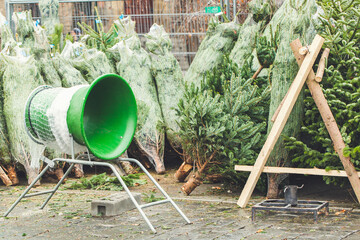 Pines and green netting tube in a farm market. No people buying Christmas trees. Selective focus,...