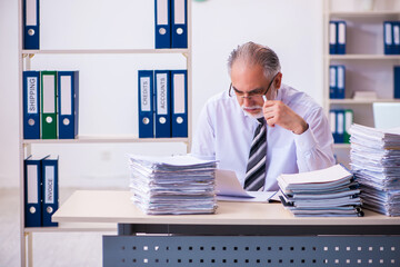 Fototapeta premium Old male employee unhappy with excessive work in the office