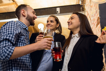 Laughting. Happy co-workers celebrating corporate event after tensioned work day. Look delighted, friendly, cheerful. Drinking beer. Concept of office culture, teamwork, friendship, holidays, weekend.