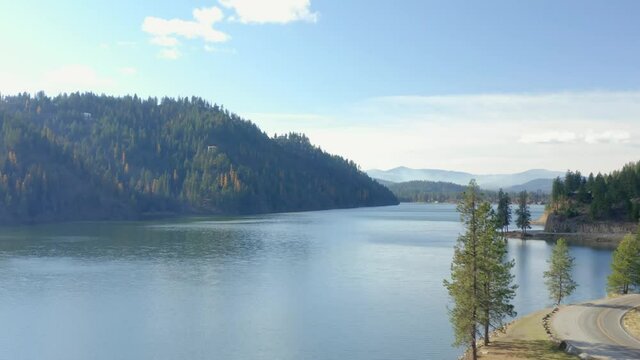 Scenic view over Fernan lake past trees and rural road in Idaho