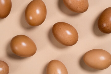 Brown organic chicken eggs. Fresh chicken eggs on a beige background. Eco-friendly production. View from above.