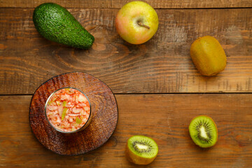 A glass of kiwi apple cocktail smoothies on a wooden table on a stand next to a kiwi apple avocado