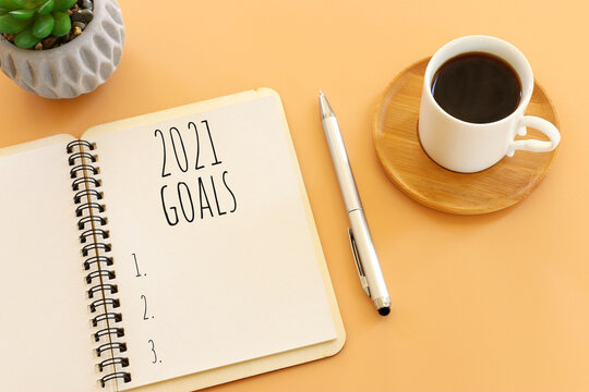 Business Concept Of Top View 2021 Goals List With Notebook, Cup Of Coffee Over Pastel Yellow Background