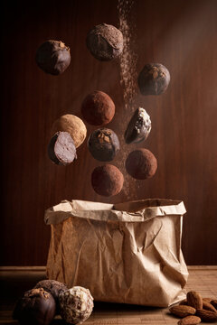 creative photography composition of delicious floating chocolate truffles and and craft paper bag on wooden background