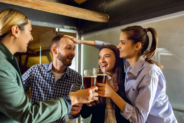 Clinking. Happy co-workers celebrating corporate event after tensioned work day. Look delighted, friendly, cheerful. Drinking beer. Concept of office culture, teamwork, friendship, holidays, weekend.