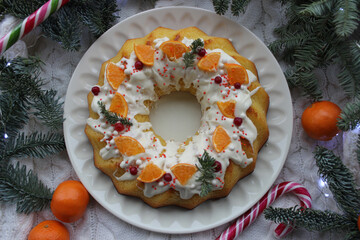 Christmas round shaped dessert is decorated with tangerine slices and coniferous twigs
