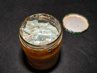 A jar of jam that has deteriorated and moldy from improper storage.