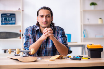 Young man repairing skateboard at workshop