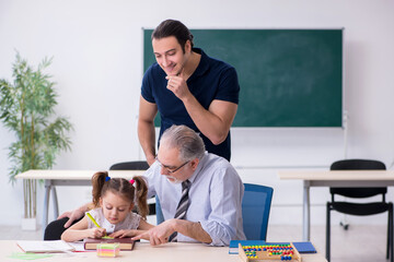 Young parent, old male teacher and little girl in the classroom