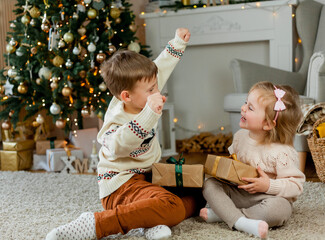 Christmas. Happy kids open gifts near the Christmas tree. Holidays.