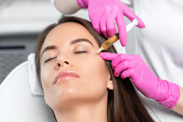 Cosmetologist does prp therapy on the face of a beautiful woman in a beauty salon. Women's...
