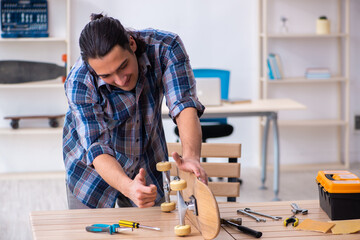 Young man repairing skateboard at workshop