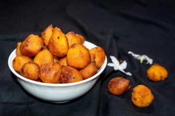 Sugar palm fritters or taler bora in a white bowl on black cloth texture background with white crepe jasmine flower.