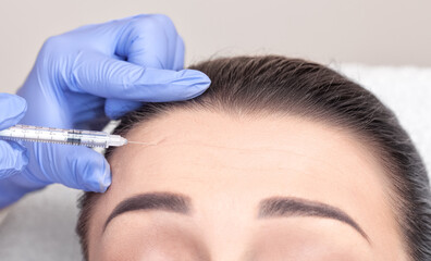 Cosmetologist makes rejuvenating anti wrinkle injections on the face of a beautiful woman. Female...