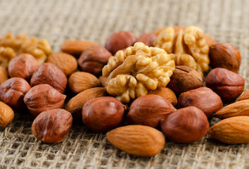 Hazelnuts, walnuts, and almonds lie on a factory-made sackcloth. Nuts are a high-calorie and healthy product.