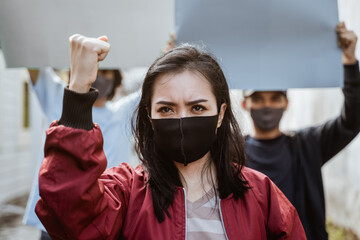 Portrait female students demonstrating with their friends holding blank paper in the background...