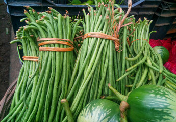 Bunch of fresh organic asparagus bean or yardlong bean vegetables in a wicker basket for selling on the market.