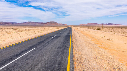 A tarmac highway cuts through the dry, arid landscape of the Namib Desert near Aus, Namibia.
