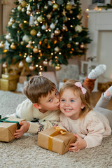 Fototapeta na wymiar Christmas. Happy kids open gifts near the Christmas tree. Holidays.