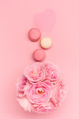Flowers roses and sweets macaroons on pink background. Valentines day concept. Flat lay, top view, copy space.