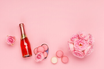 Obraz na płótnie Canvas Flowers, bottle of wine, sweets on pink background. Valentines day concept. Flat lay, top view, copy space.