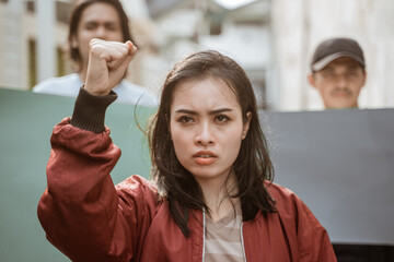 Portrait female students demonstrating with their friends in the background