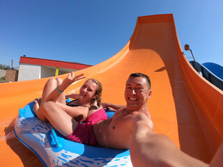 Happy couple having fun in water slides. Amusement, aqua.