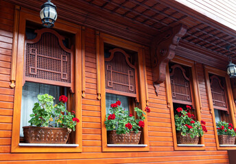 Fototapeta na wymiar Hotel windows decorated with red pelargoniums