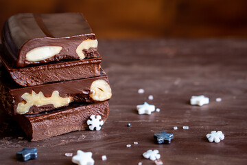 Organic food snack tasty sweet dessert milk dark chocolate bar macro closeup broken slide piece and fruit orange raspberry hazelnut nuts on cocoa cacao powder wooden table for new year Christmas gift