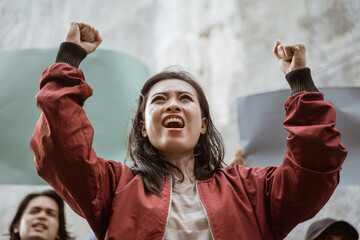 Portrait female students demonstrating with their friends holding blank paper in the background
