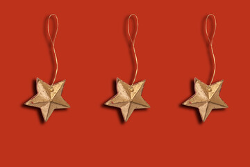 
Three festive golden Christmas star - wooden toy on a Christmas tree on a red background. With...