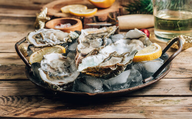 Oysters with lemon on a vintage dish on a rustic wooden background with a festive decor. Christmas...