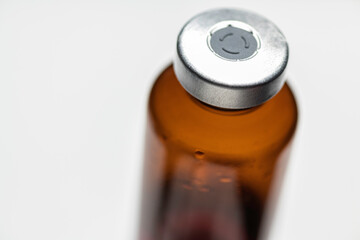 Macro Shot Of Amber Vaccine Vial In White Background