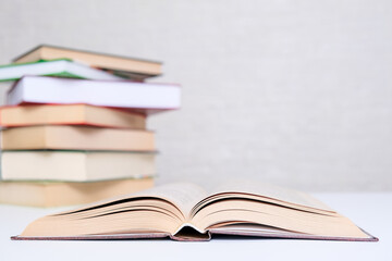 Love of books, reading, a stack of books lying on the table and open book in front of them, copy space