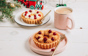 Mini cheesecake with cranberries on a white wooden table with Christmas decorations. Selective focus