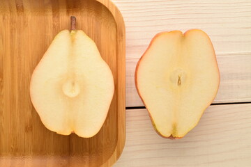 Two halves of sweet, red pears on a white wooden table, close-up.