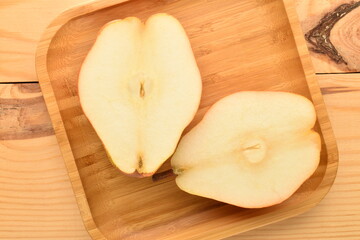 Fresh sweet, red pears in a bamboo plate on a wooden table, close-up.