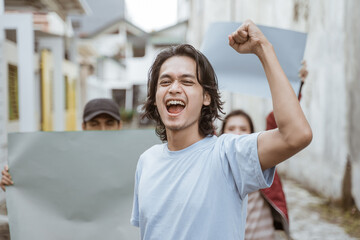 Portrait male students holding blank paper who are burning with enthusiasm doing a demonstration...