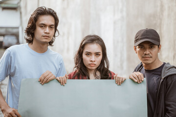 Portrait students holding blank paper who are burning with enthusiasm doing a demonstration together