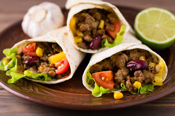 Burrito with beef, lime, pepper, garlic and vegetables, on a plate. Mexican food.