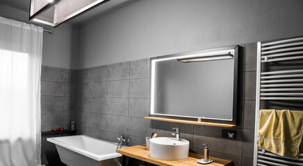 Bathroom in a concrete style with a bath, sink and big mirror.