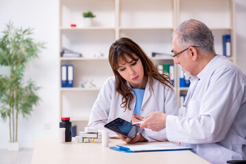 Fototapeta premium Old male doctor radiologist and his young female assistant in th