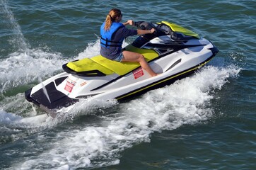 Angled overhead close-up view of a young woman riding on a jet-ski.