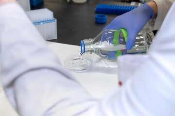 Manos vertiendo botella de liquido en laboratorio