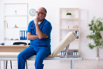 Old male doctor working in the clinic