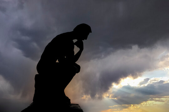 Sculpture thinking man in sunset silhouette. Concept photo.