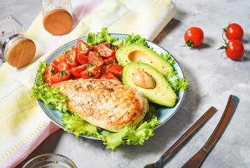 Caprese lunch bowl with grilled chicken and avocado on concrete background