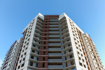 Contemporary urban architecture. Facade of a multi-storey building under construction. Brick building under construction.